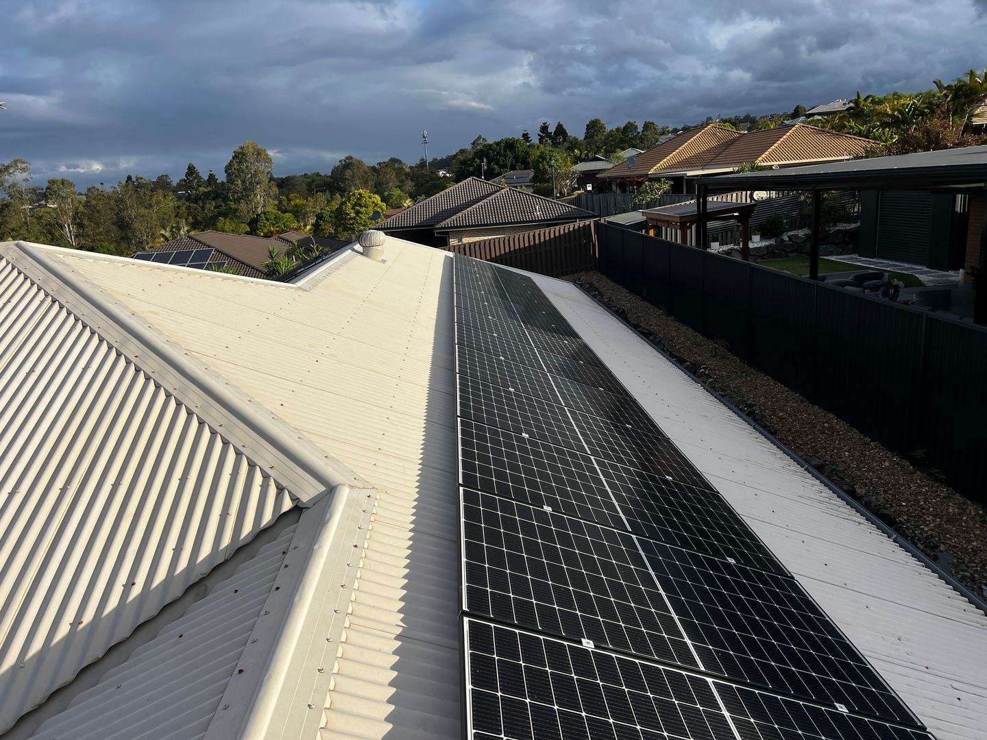 Close view along a freshly installed row of black solar panels on a metal roof